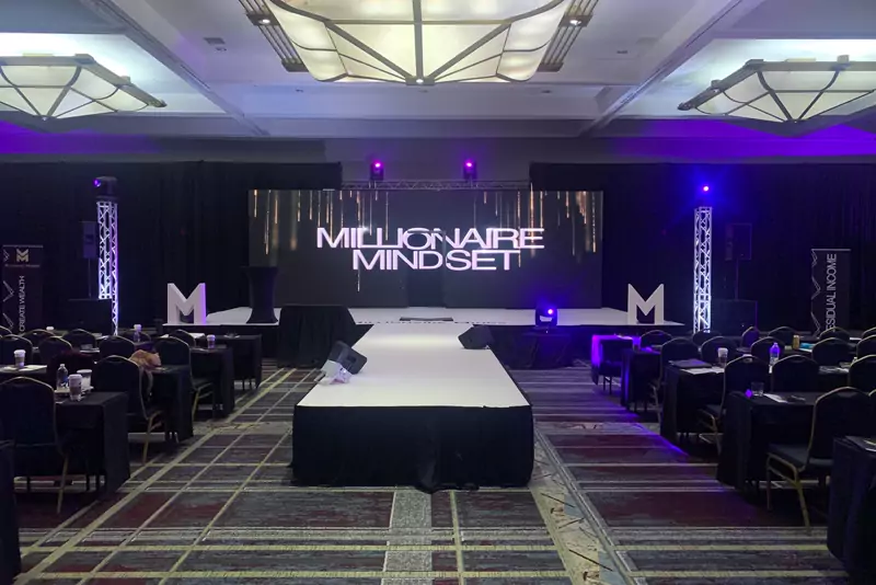 Ballroom general session with a runway stage, LED screens and branded set pieces