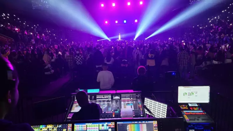 Concert crowd under purple moving lights, seen from front of house