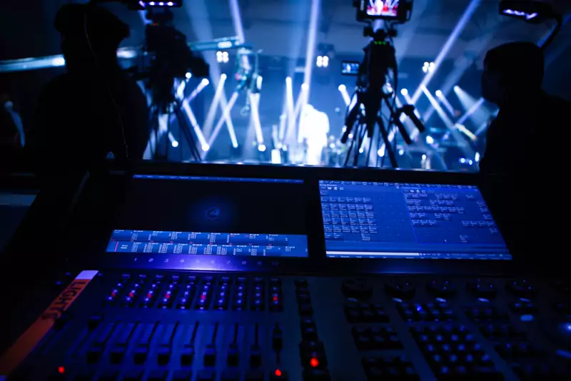 Lighting console in front of a stage with moving-light beams
